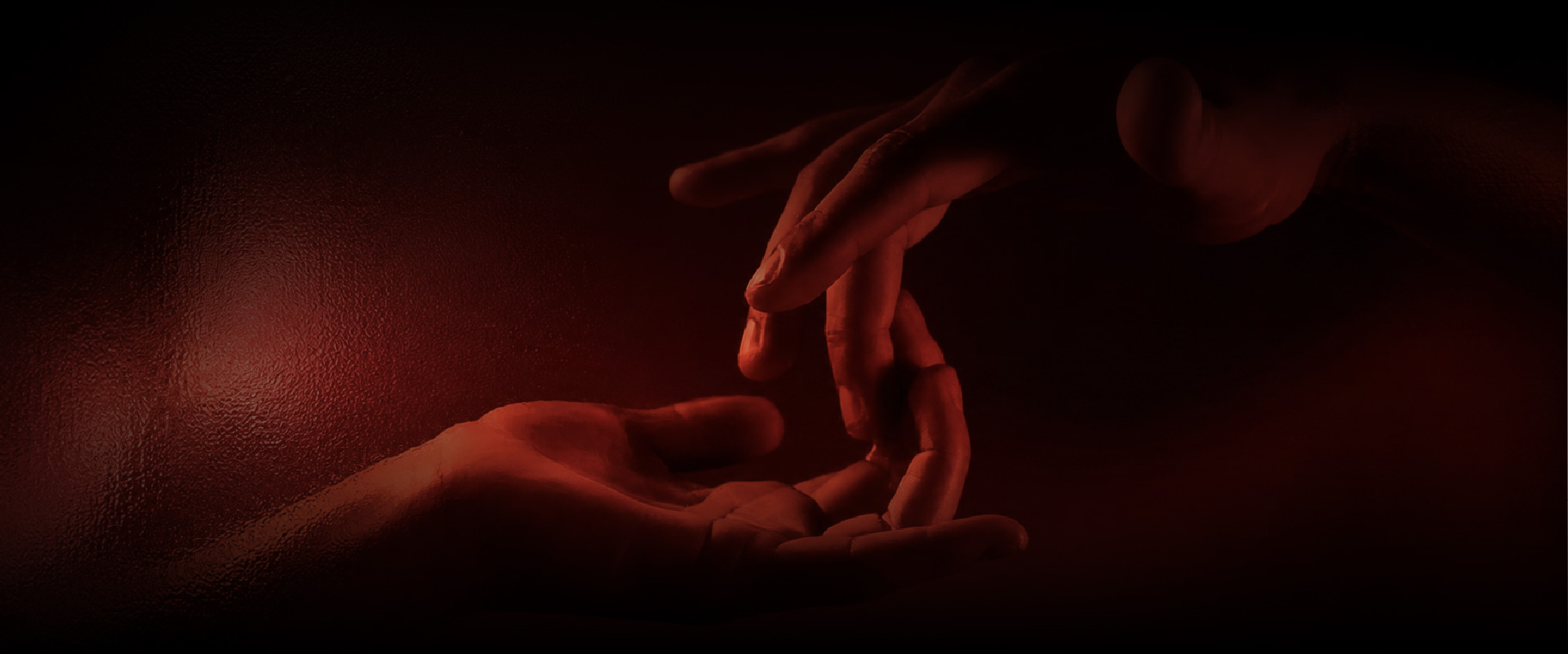 Manos en luz roja que evocan el tacto consciente del masaje tántrico en G.nesis, Medellín